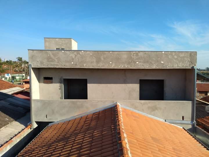 Fachada de sobrado com reboco cinza e telhado de cerâmica